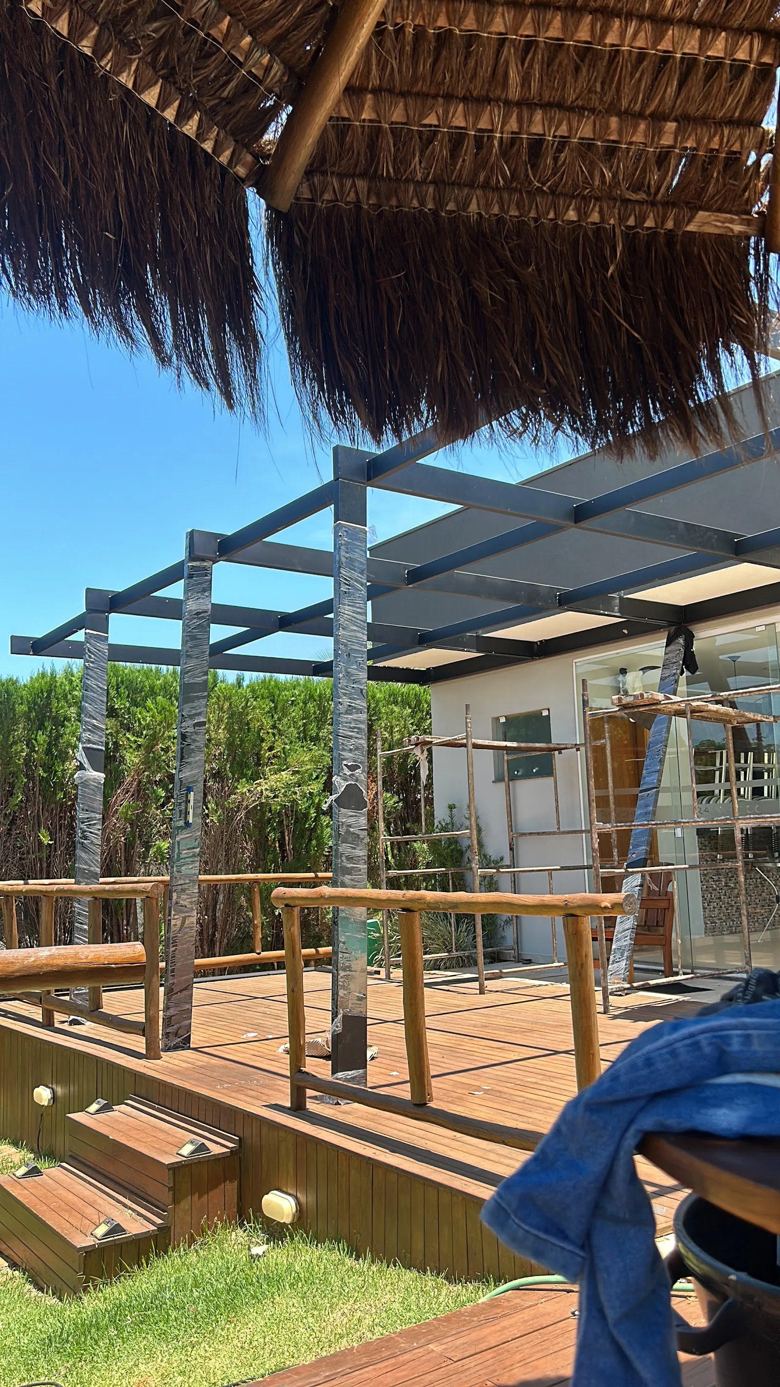 Pergolado com estrutura metálica sobre deck de madeira